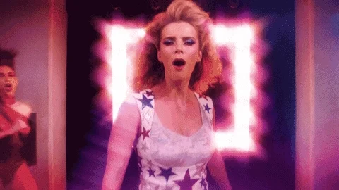 Gif of Glow's TV intro with the wrestlers dancing through a hallway