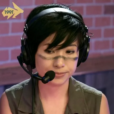 Une personne portant des écouteurs, avec un maquillage camouflé sur le visage, regardant vers le bas.