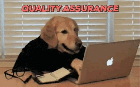 GIF of a dog's sticking out of a t-shirt, with human hands coming out of the bottom of the t-shirt, typing at a keyboard as if the hands belonged to the dog.  (The human is obviously hidden under the table.)  Captioned "quality assurance"